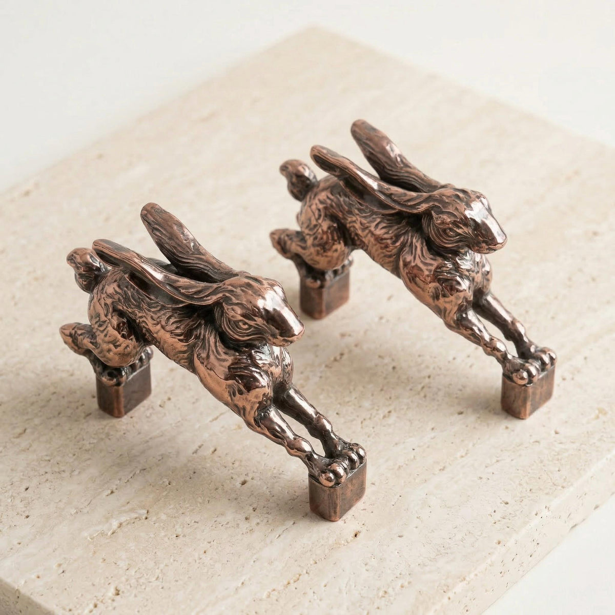 Two hopping hare handles in antique copper on linen