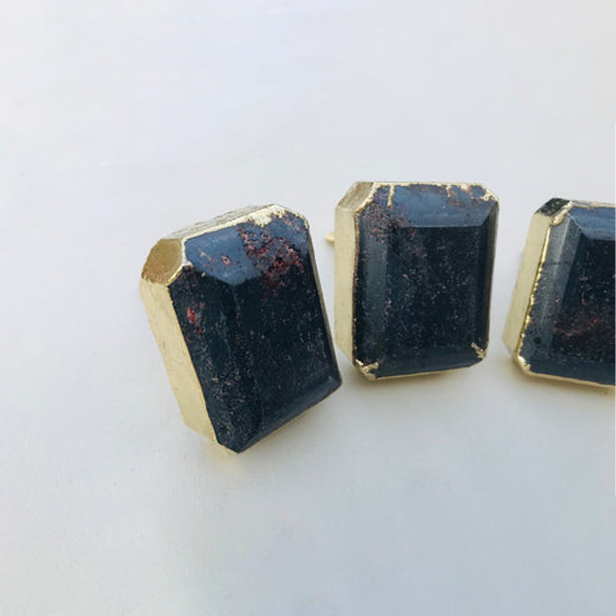 Emerald-cut hematite knobs seen low, reddish glints in the dark stone
