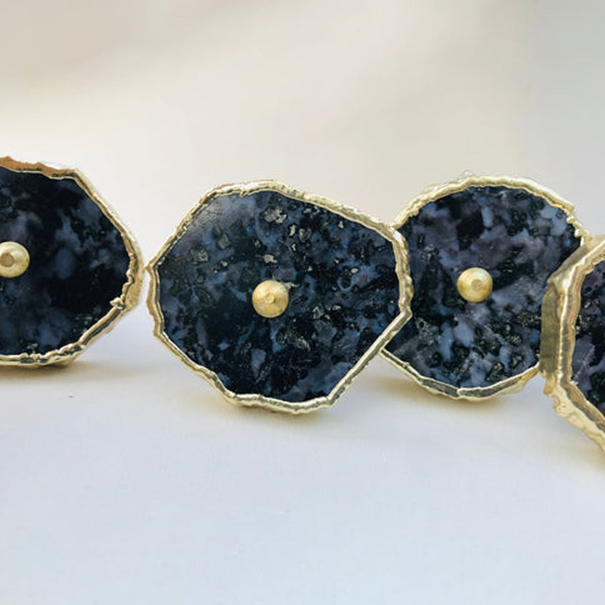 Row of gabbro slice cabinet knobs seen low across a white surface