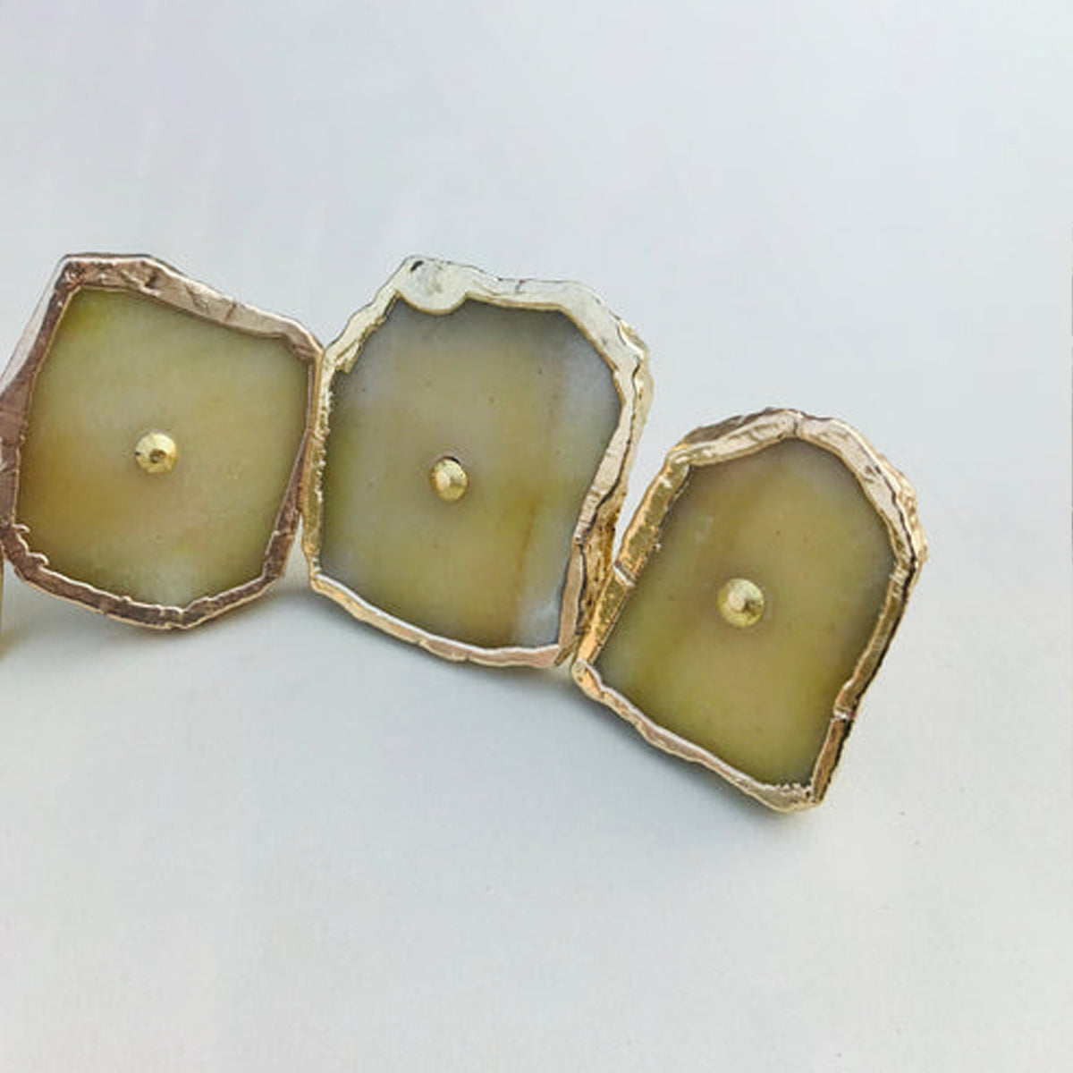 Three mustard agate slice knobs in a row, each with a brass center pin