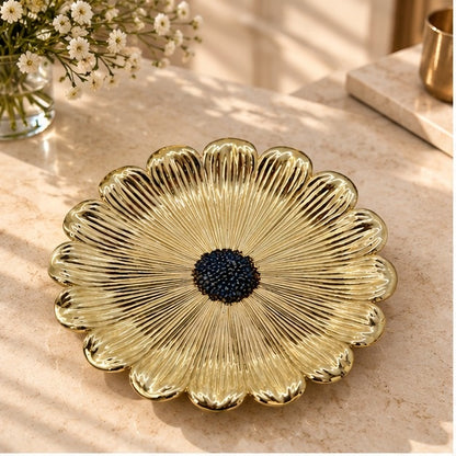 Gold flower dish with a dark beaded center on a marble counter