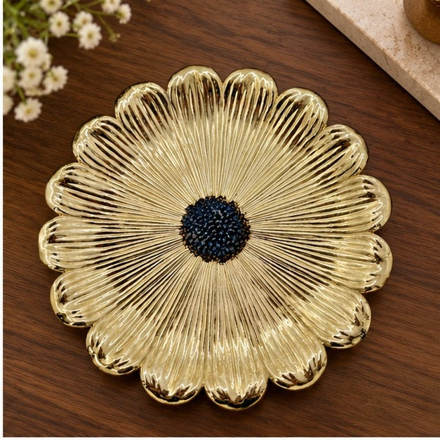 Gold flower dish with a dark beaded center on a wooden table