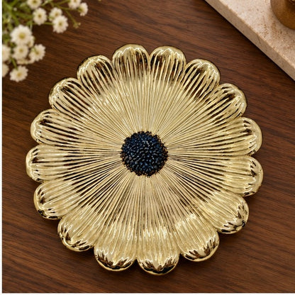 Gold flower dish with a dark beaded center on a wooden table