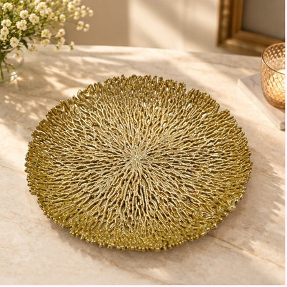 Round coral openwork tray in gold on a marble counter with flowers and a candle