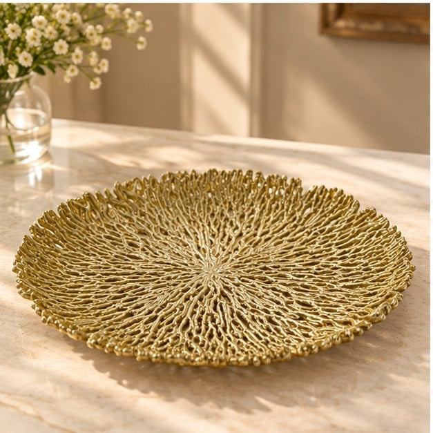 Round coral openwork tray in gold on a marble counter