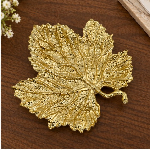 Leaf-shaped tray in gold on a wooden table