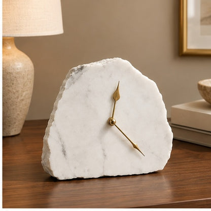 White marble desk clock on a wooden table with a lamp