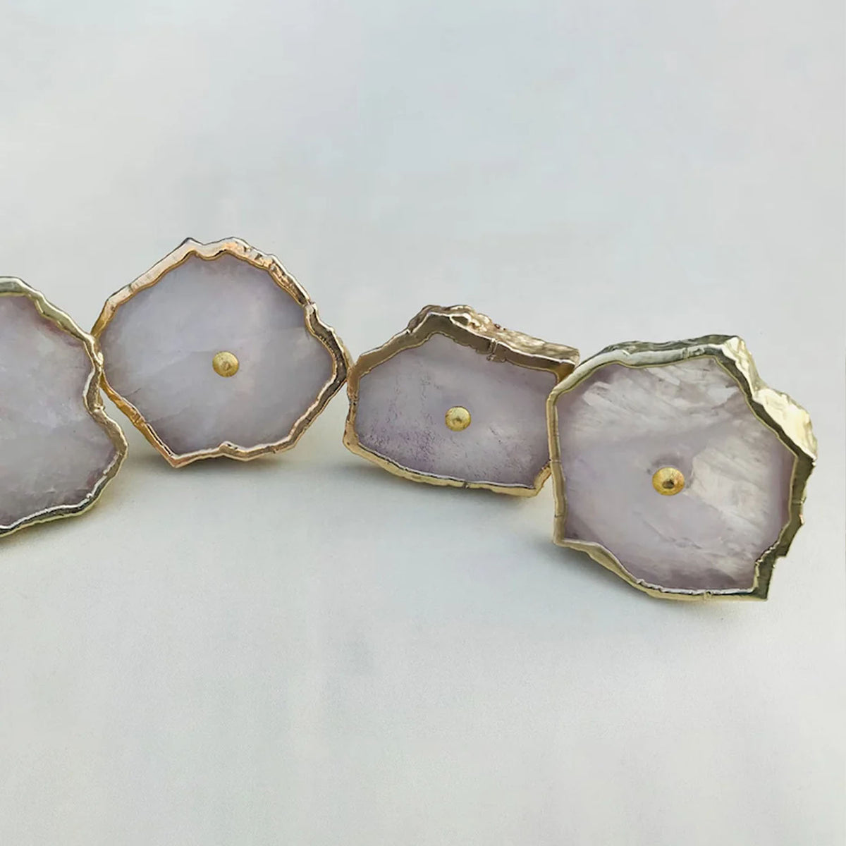 Rose quartz slice knobs in a curve, the rightmost knob tilted toward the camera