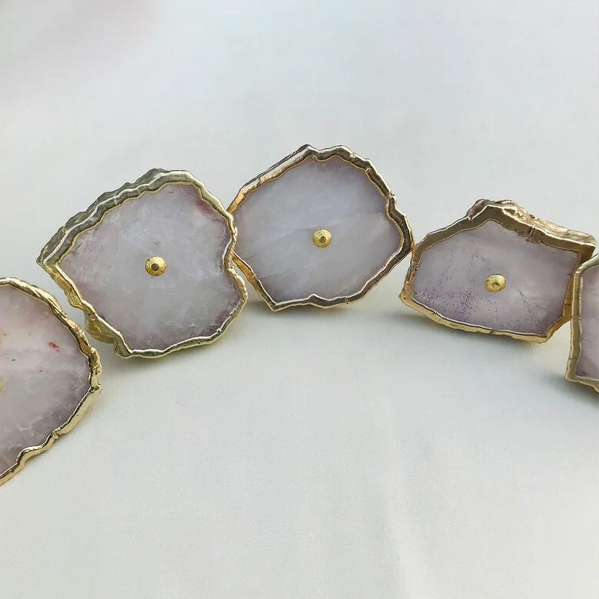 Rose quartz slice knobs with gold edges and center pins, close-up