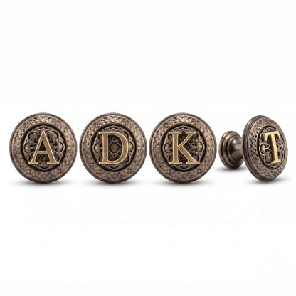 Four antique brass initial knobs reading A, D, K and T, with the T knob turned to show its stem