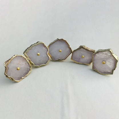 Five pale pink rose quartz slice knobs laid in a curve, each with a gold edge and center pin