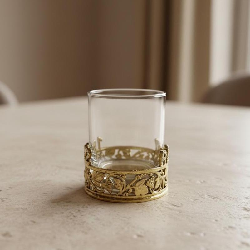 Empty glass in the gold vine band, side view on a pale stone table