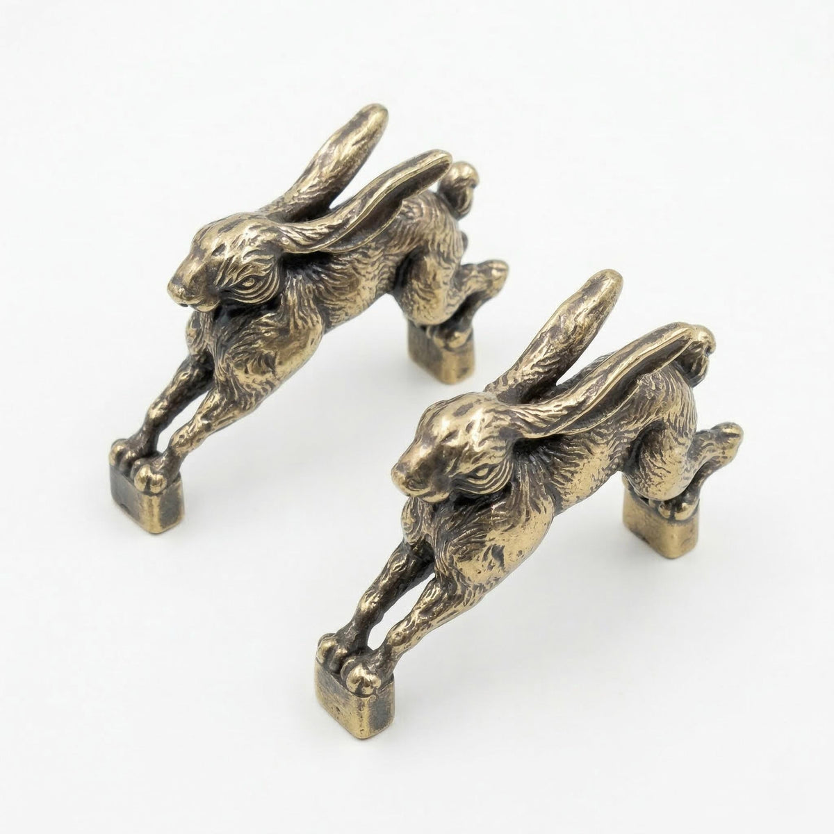 Two antique brass hopping hare handles angled toward the camera