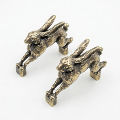 Two antique brass hopping hare handles angled toward the camera
