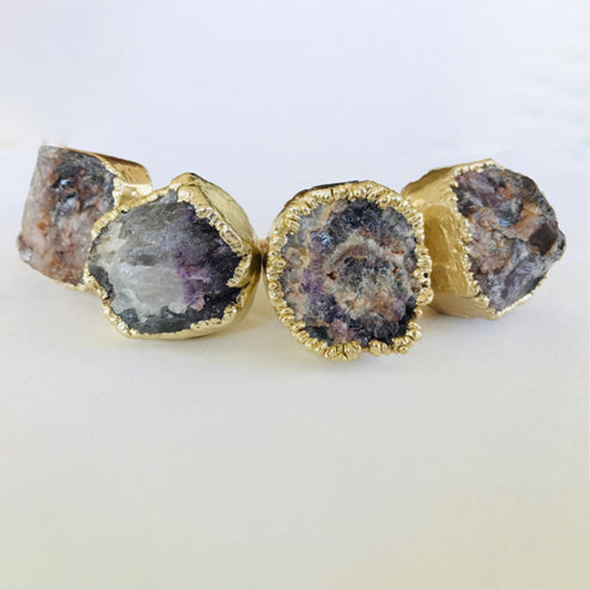 Four raw amethyst knobs in a row, crystal centers ringed in gold