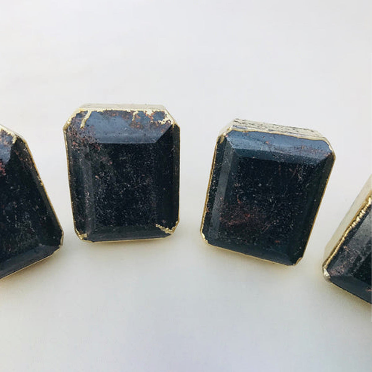 Emerald-cut hematite knobs, dark gray-black with fine glints, in gold bezels