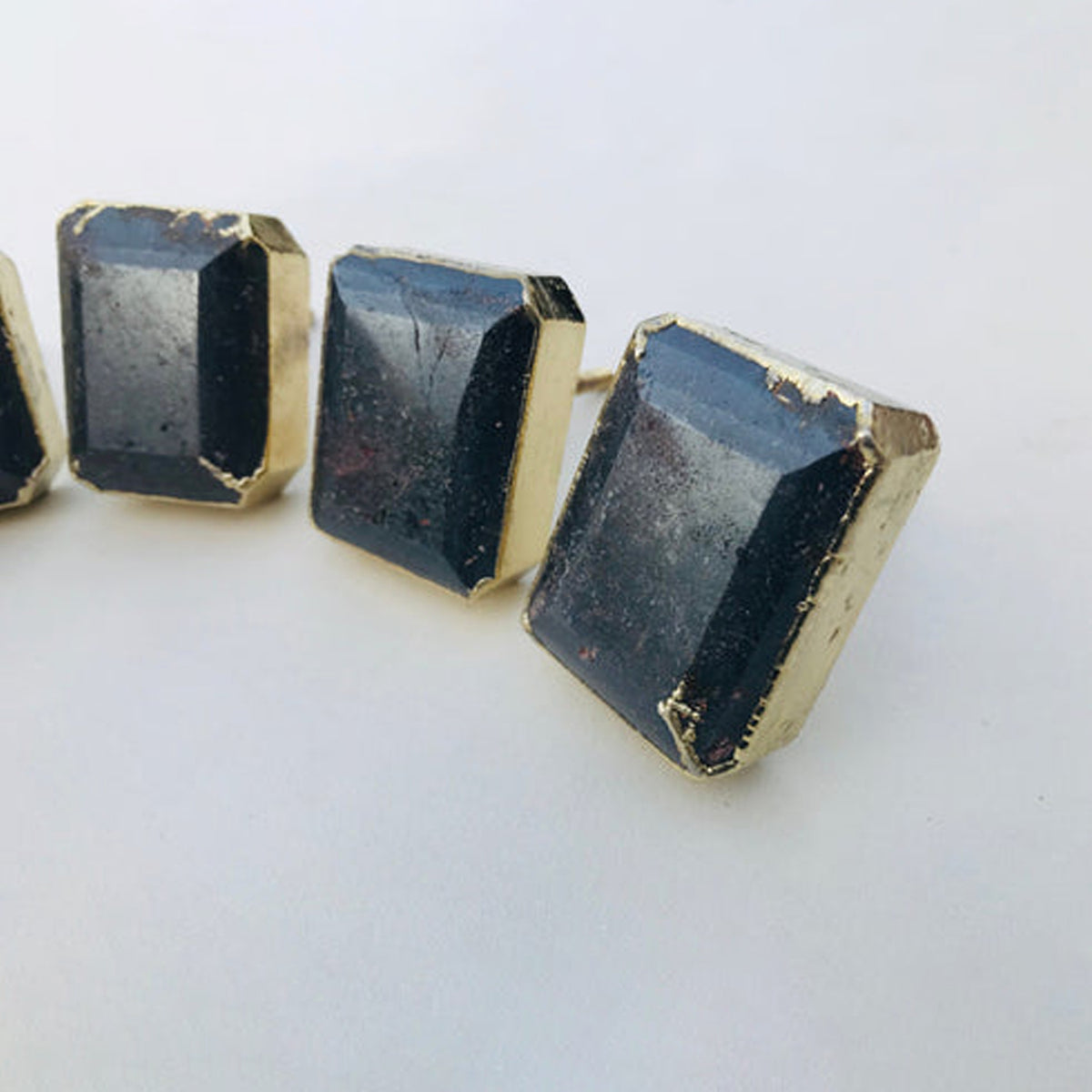 Three emerald-cut hematite knobs angled to show their faceted sides