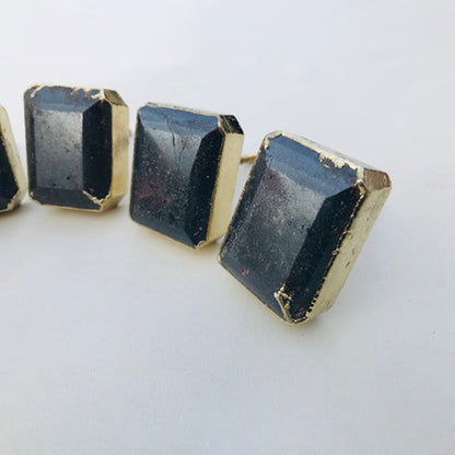 Three emerald-cut hematite knobs angled to show their faceted sides