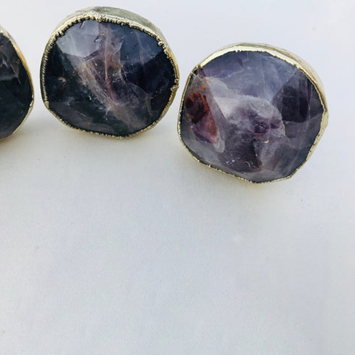 Two faceted amethyst knobs up close, one with a reddish violet center
