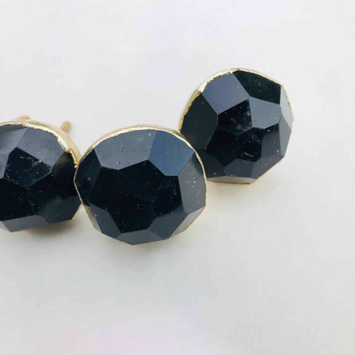 Faceted black obsidian knobs in a curve, the middle one closest to the camera