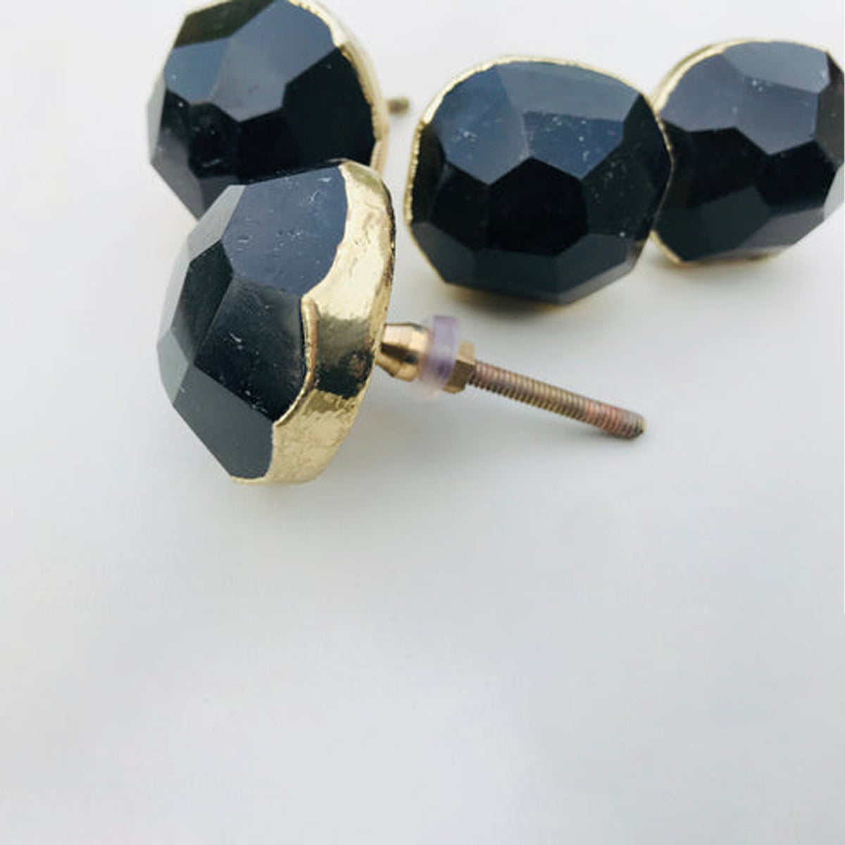Faceted black obsidian knob turned to show its gold collar and bolt