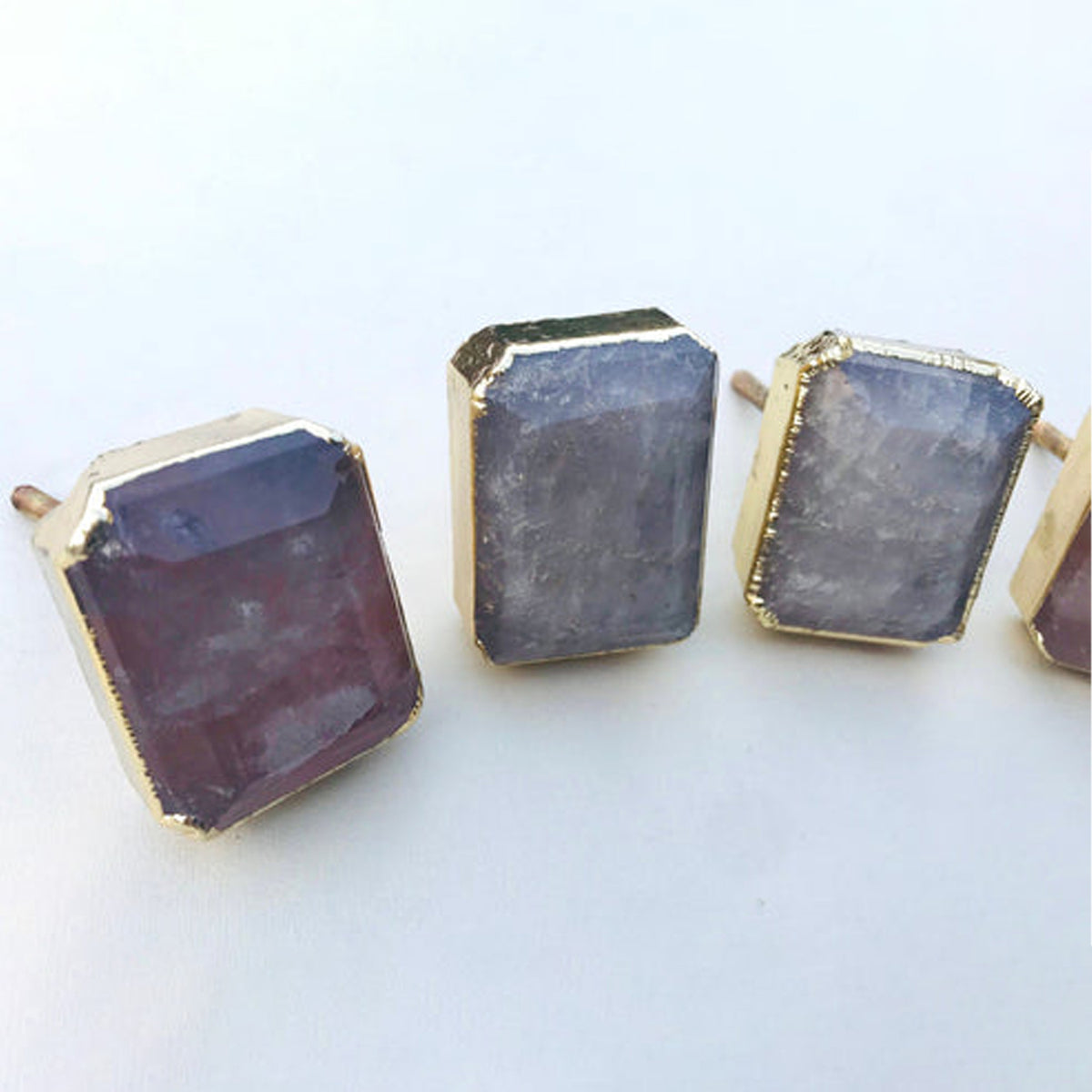 Emerald-cut quartz knobs seen from the left, the nearest one tinted pink