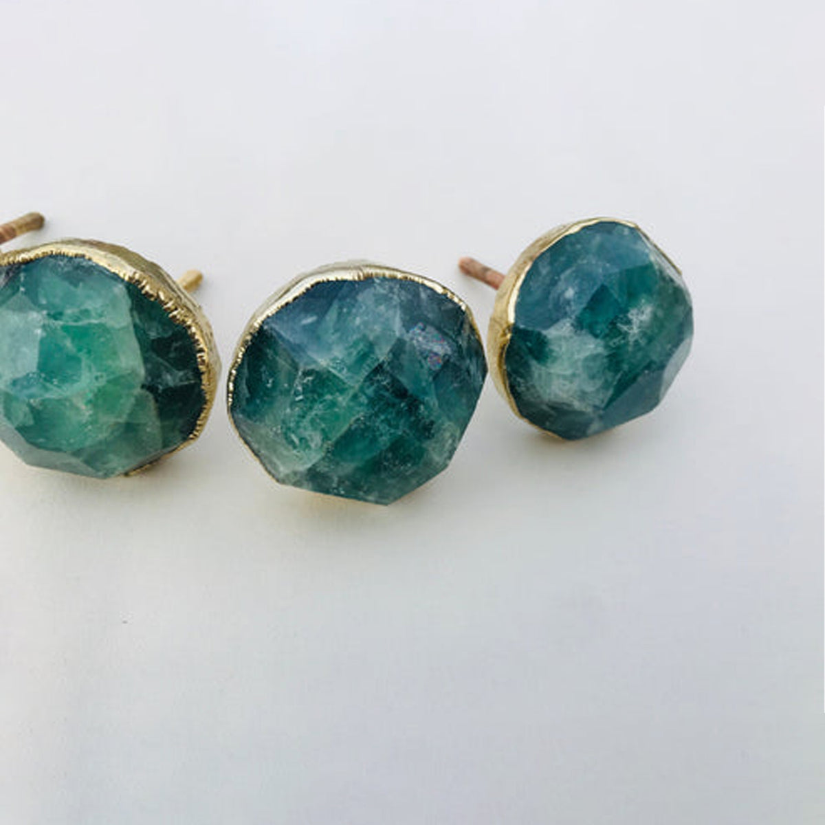 Three faceted green fluorite knobs in a row, deep teal with paler streaks