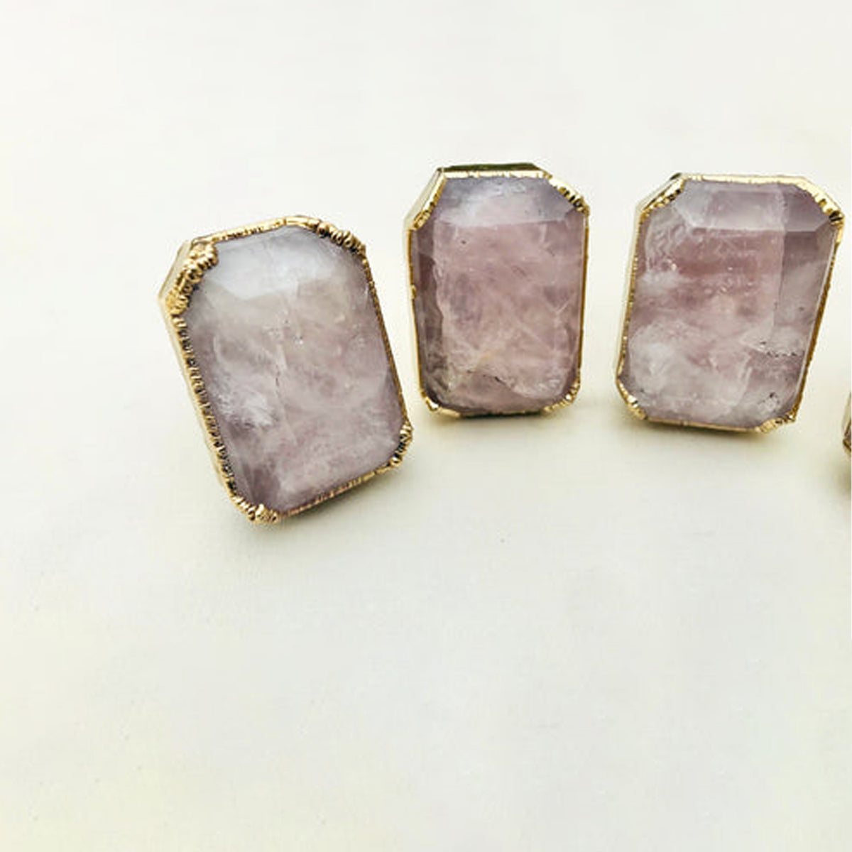 Three emerald-cut rose quartz knobs in a row, faceted pale pink tops