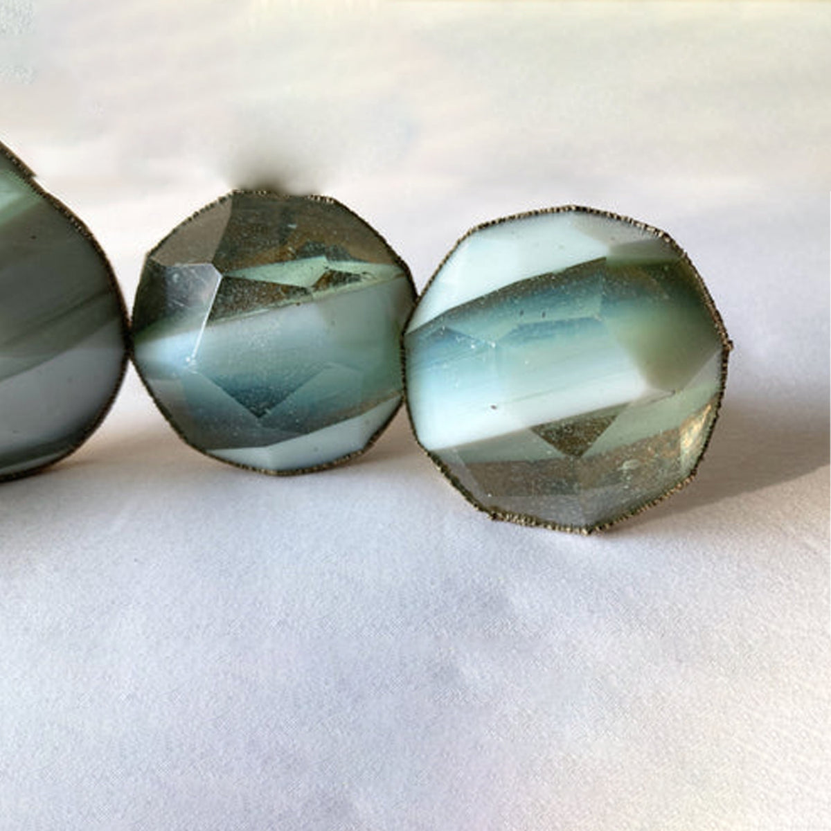 Close-up of faceted knobs banded in milky white and gray-green