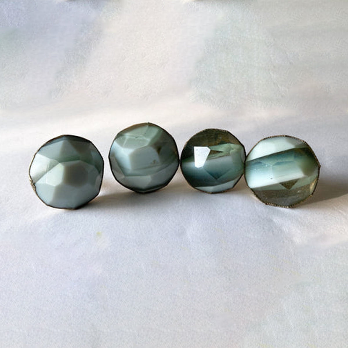 Four round faceted cabinet knobs in smoky green and white