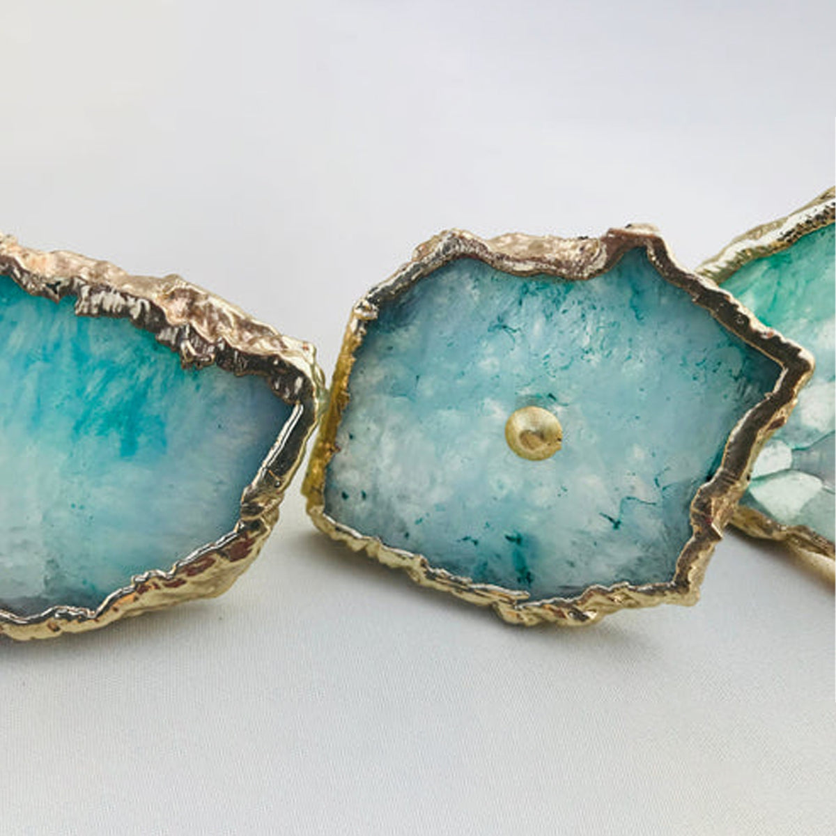 Row of aqua agate slice knobs, the middle one centered with its brass pin