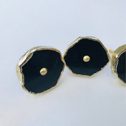 Close-up of two black agate slice knobs with gold rims and brass center pins