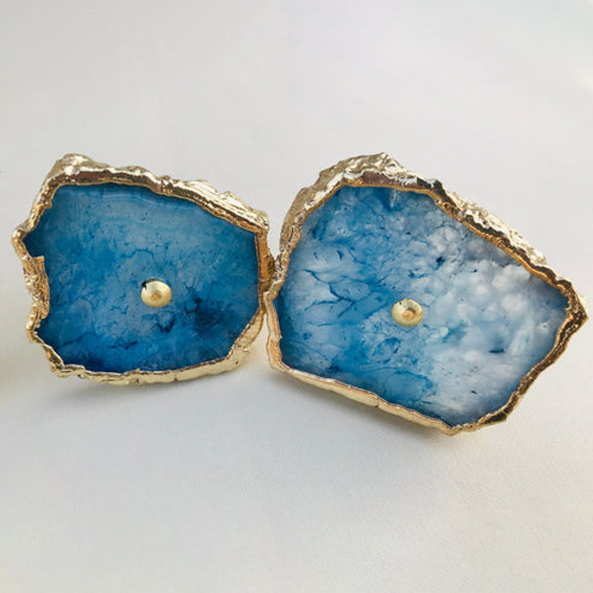 Two blue agate slice cabinet knobs with pale centers and gold edges