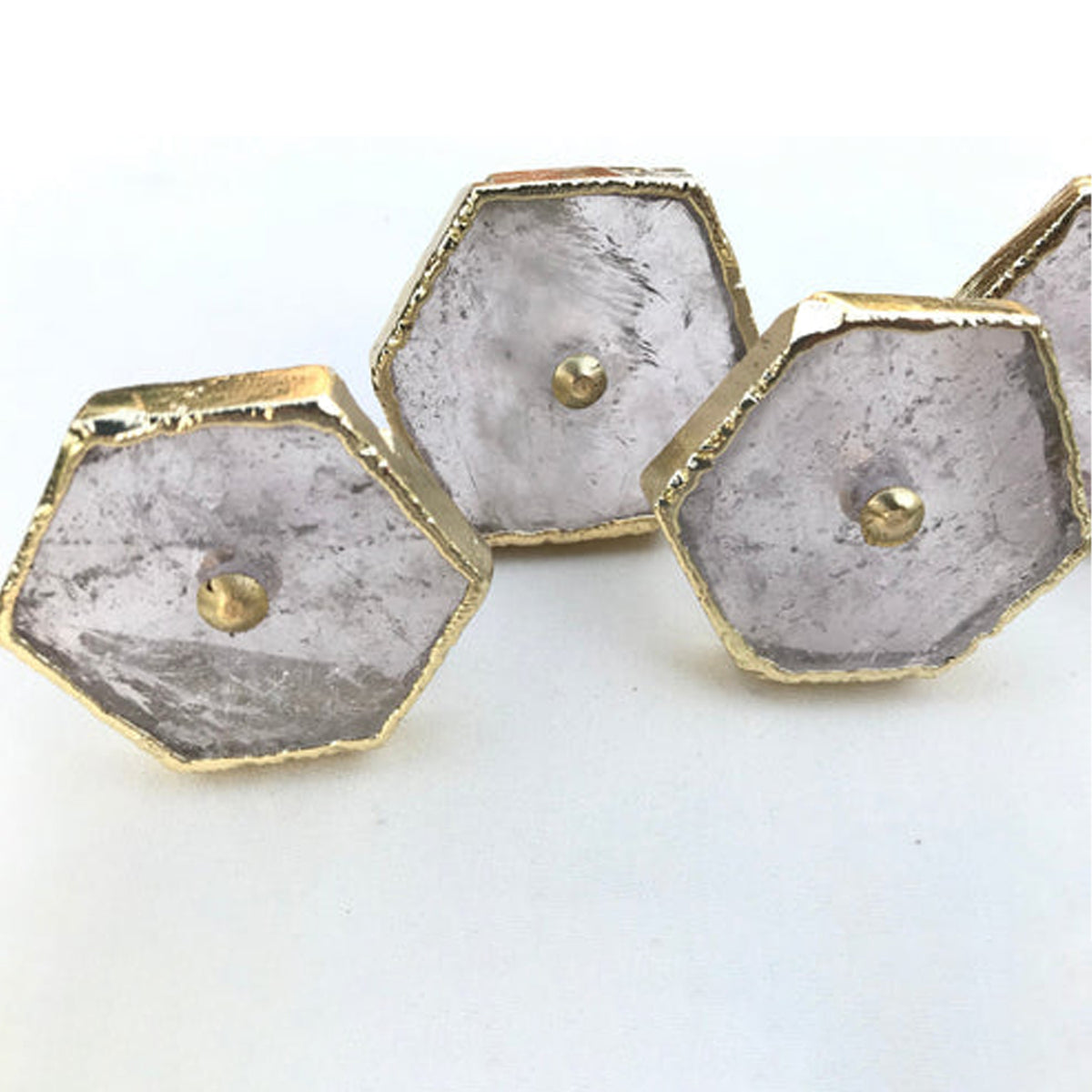 Three clear quartz hexagon knobs up close, cloudy crystal with brass center pins