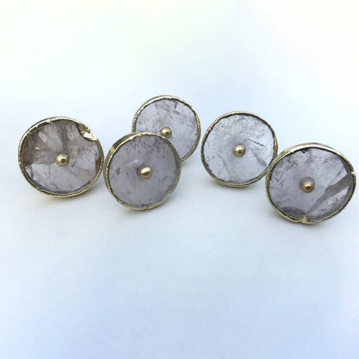 Four round clear quartz cabinet knobs with gold rims and brass center pins