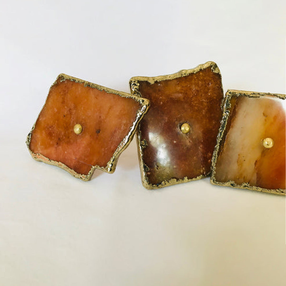 Three golden agate slice knobs in a row, amber, brown and cream tones