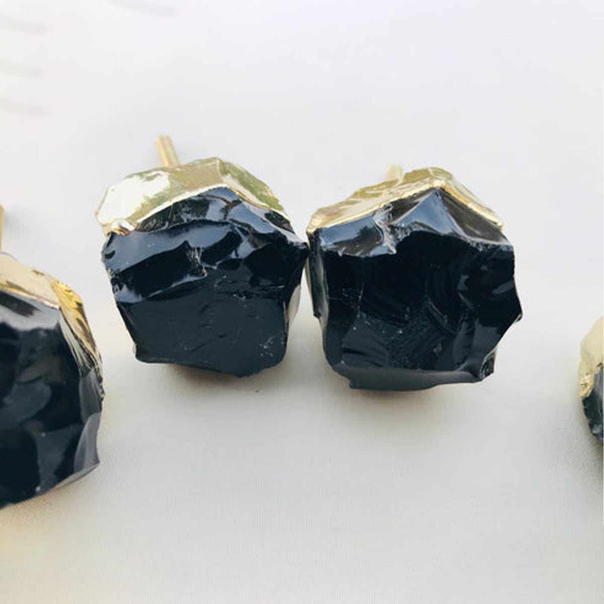 Close-up of two raw black obsidian knobs, their rough glassy surfaces catching the light