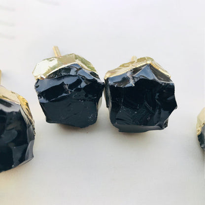 Close-up of two raw black obsidian knobs, their rough glassy surfaces catching the light