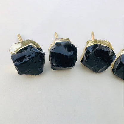 Row of raw black obsidian knobs with gold collars and their bolts