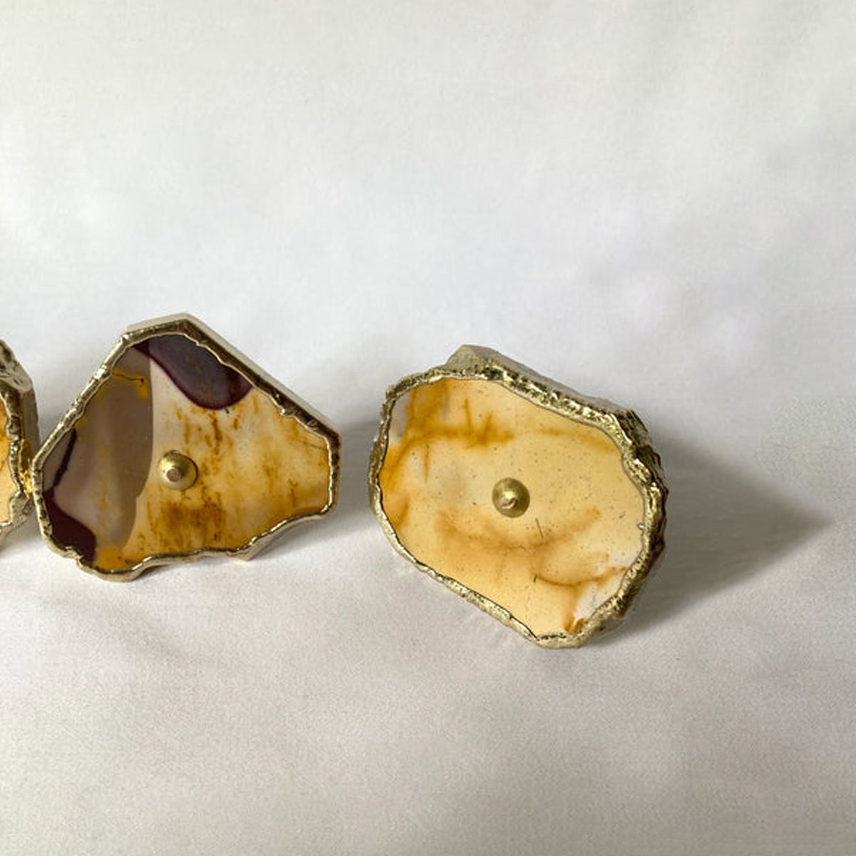 Two mookaite slice knobs, one with a deep red edge, seen low
