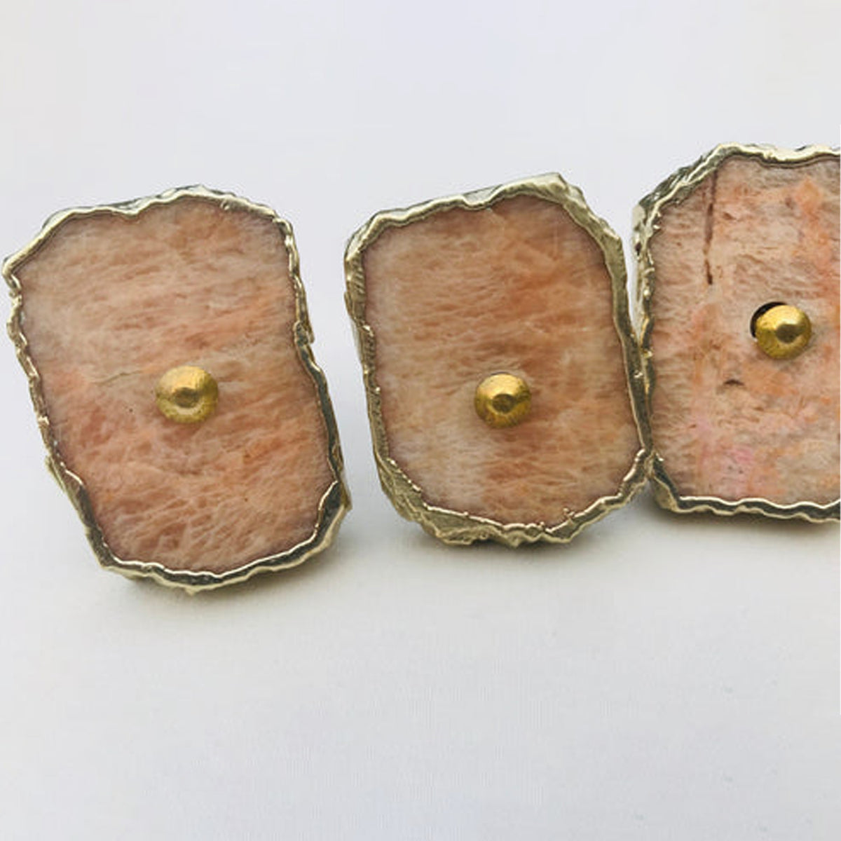 Three rectangular peach moonstone slice knobs with gold rims and brass center pins
