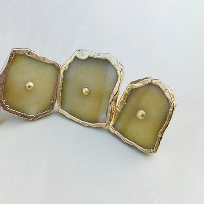 Three mustard agate slice knobs in a row, each with a brass center pin