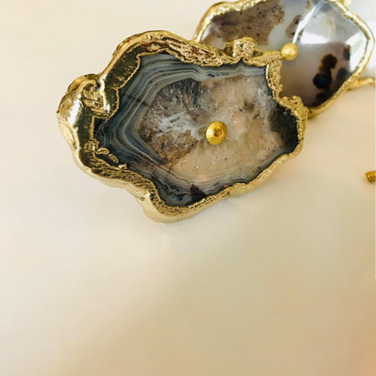 Close-up of a gray agate slice knob with dark banded rings and a gold edge
