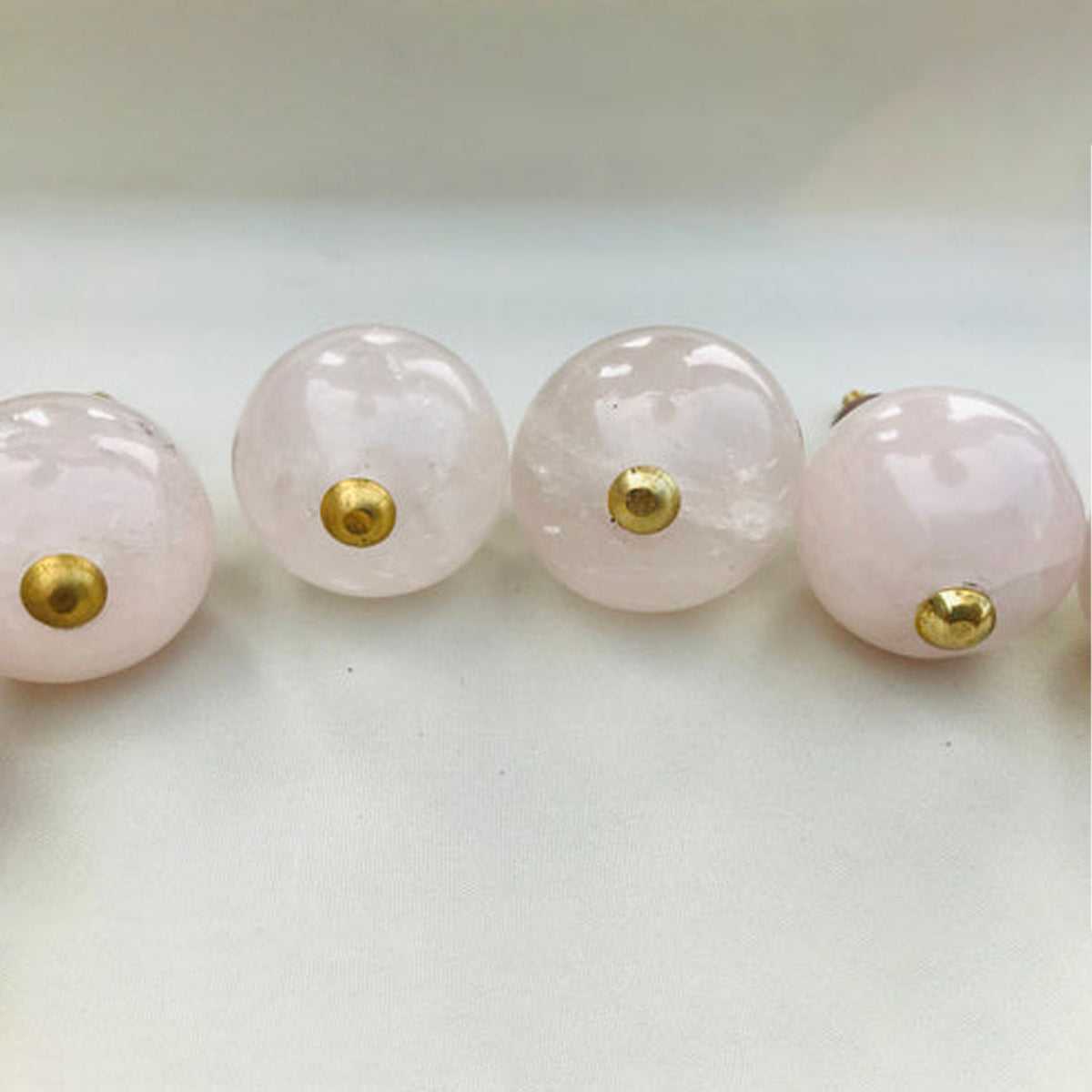 Close-up of polished pale pink rose quartz sphere knobs in a row