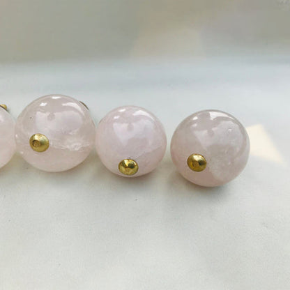 Close-up of polished rose quartz sphere knobs with gold studs