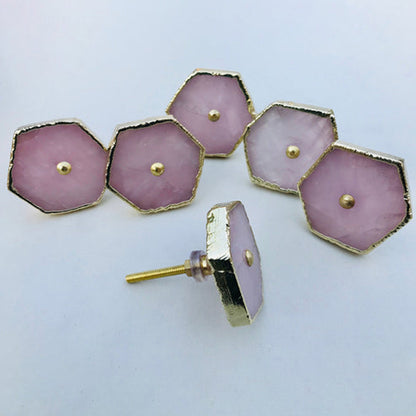 Five hexagonal rose quartz cabinet knobs with gold edges, one turned to show its bolt