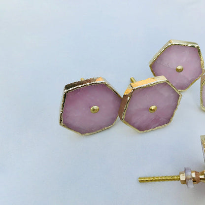 Close-up of rose quartz hexagon knobs with brass center pins and gold edges