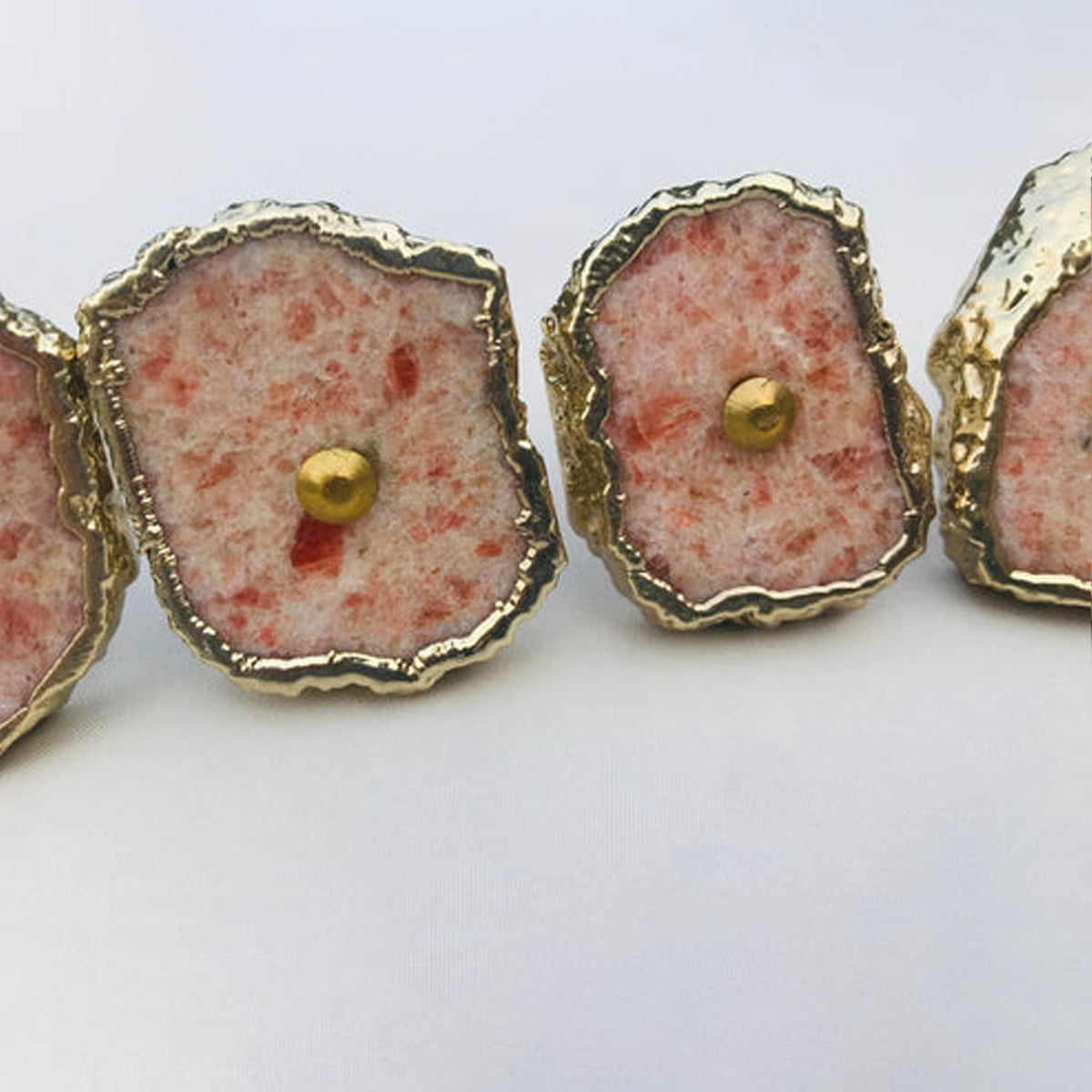 Row of sunstone slice knobs with brass center pins, seen straight on