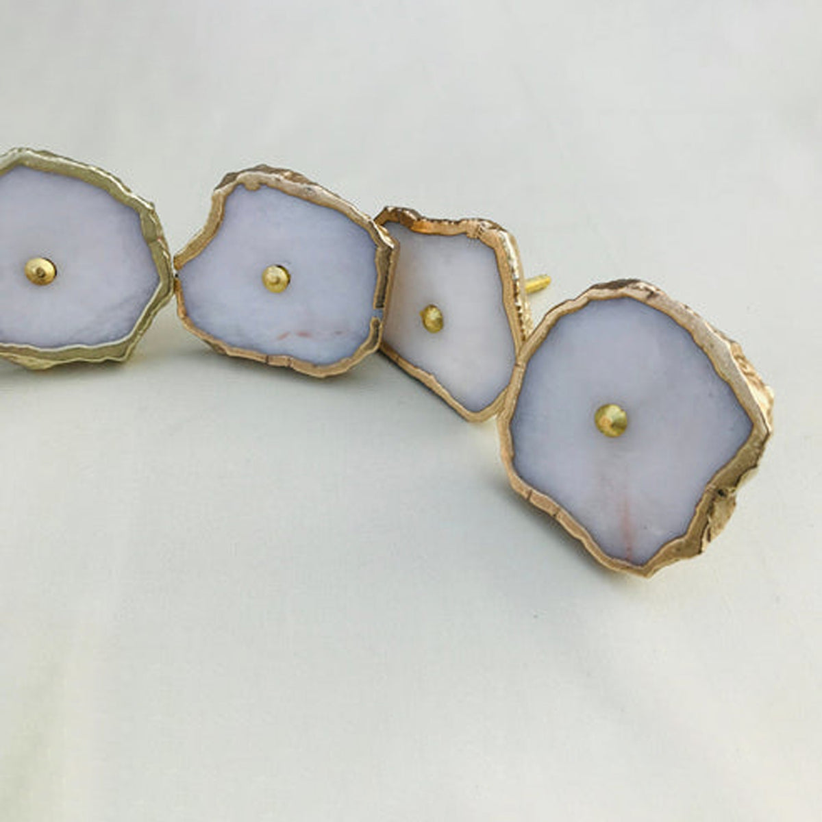 White agate slice cabinet knobs with gilded rims and brass center pins, in a curve