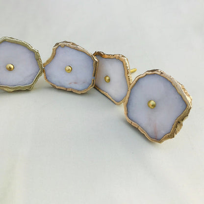 White agate slice cabinet knobs with gilded rims and brass center pins, in a curve